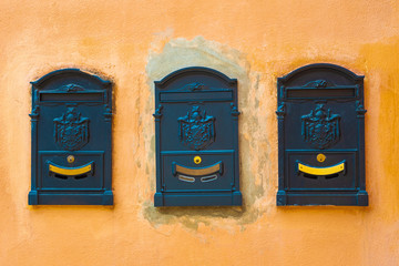 Three mailboxes embedded in the wall of a house