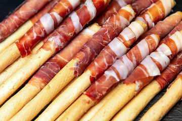 Appetizing grissini with ham. Closeup view square photo.