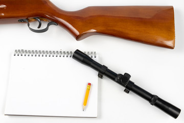A notepad for making notes and a pencil on a table with a firearm. Shooting accessories and materials for quotation.