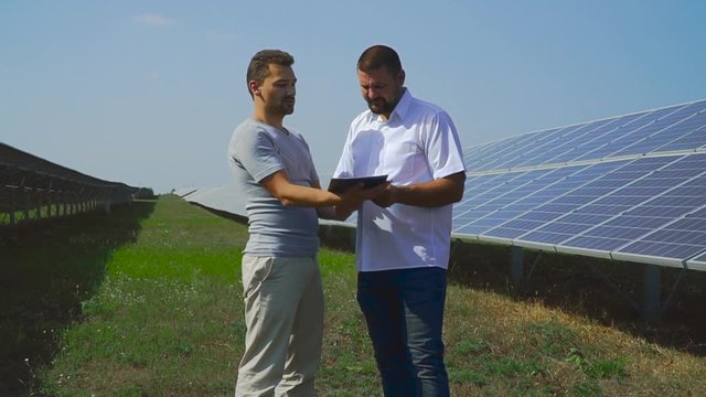 Two businessmen are discussing a project on solar batteries.