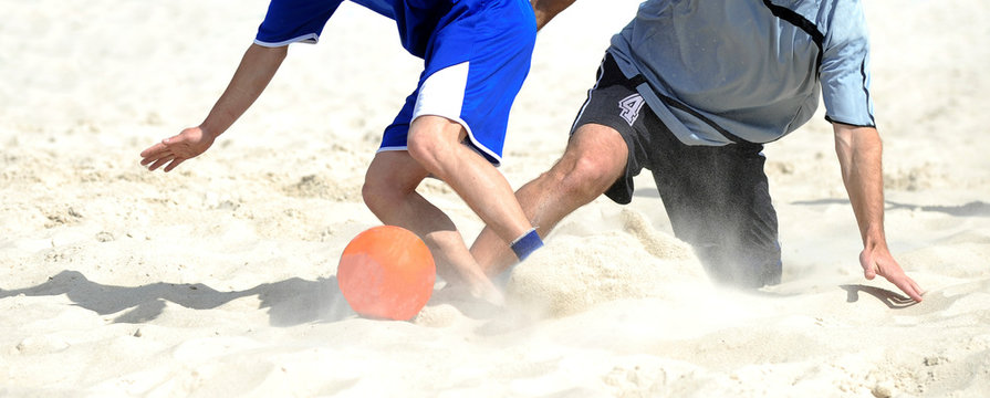 two people playing with soccer ball on the beach
