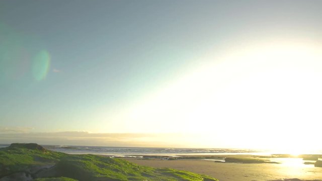 Sliding past big moss covered rocks on the beach while the sun rises in the corner