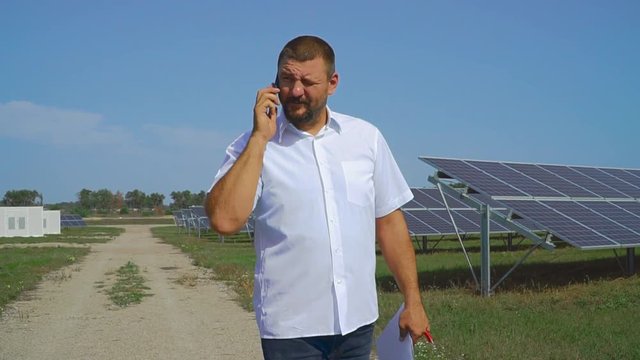 Man talking on the phone on the background of solar panels
