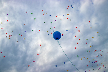 Blue balloon flies into the sky. On the textured blue sky many colorful balloons are flying.