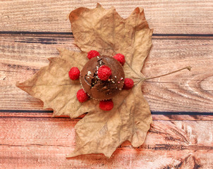 Chocolate muffin with raspberries on a big yellow leaf on a wooden background