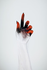 Creepy Halloween monster witch hand with white, red and black make up and long creepy fingernails...