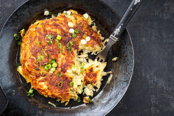 Traditional Swiss rosti as side dish with leek as top view in a frying pan with copy space right