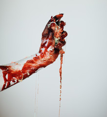Creepy bloody horror Halloween monster witch hand with white, red and black make up and long creepy...