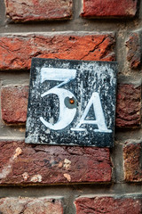 House number three A 3A painted white on a black board attached to red brick in stylised cursive font from Belgium