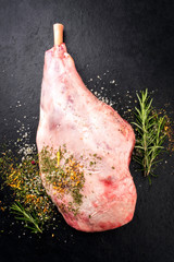 Traditional raw leg of lamb with spice and herb as top view on a slate slab with copy space