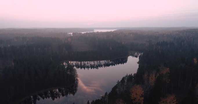 Flying over autumn forest with lakes as the sun goes down, Karkkila Finland