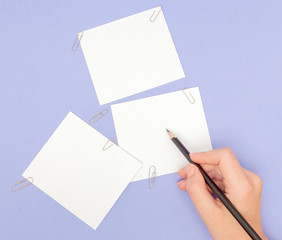 Womens hand writing on note papers on purple background. Blanks sheet of papers and color pencils on violet background. copy space