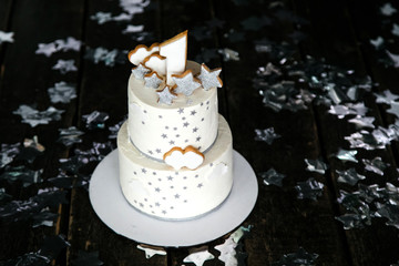 First birthday white cake with stars and one candle for little baby boy and decorations for cake smash. Black background