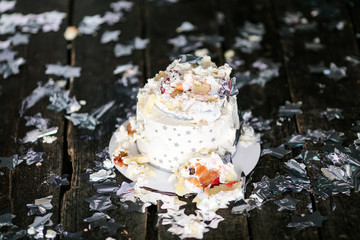 Smashed first birthday white cake with stars and one candle for little baby boy and decorations. Black background
