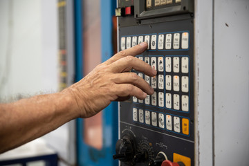 An employee presses the button on the control panel of CNC