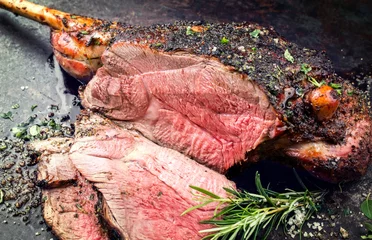 Foto auf Leinwand Traditional barbecue leg of lamb with spice and herb as top view on a metal sheet © HLPhoto