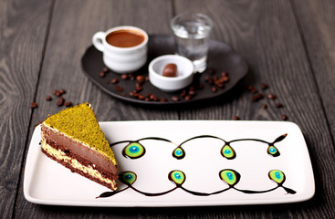 Delicious chocolate cake with a layer of green pistachio and Turkish coffee in the background