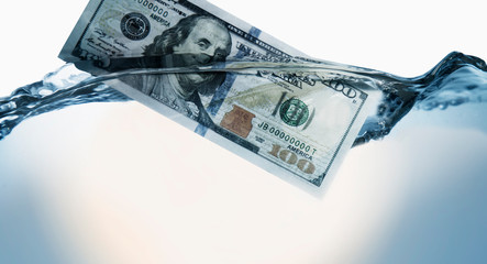 US Dollar sinking in water as symbol of global financiall crisis and uncertain future of...