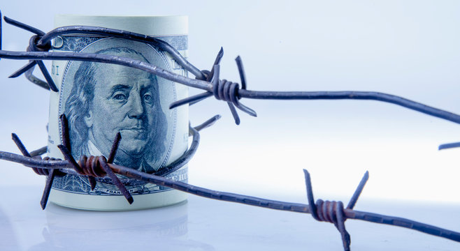 Economic Warfare, Sanctions And Embargo Busting Concept. US Dollar Money In Barbed Wire.