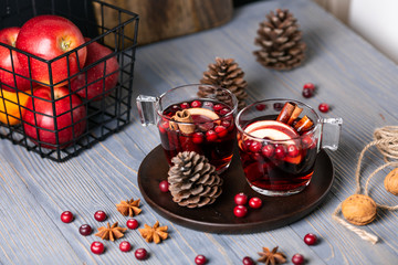 Mulled wine in glasses on a wooden background. Apples, cranberries, cinnamon, star anise, walnuts, cones
