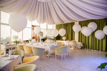 Wedding decor. Wedding tables in restaurant with white flowers and huge white balloons