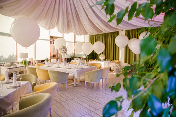 Wedding decor. Wedding tables in restaurant with white flowers and huge white balloons
