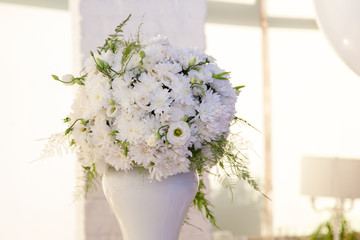 Wedding decor. Bouquet of white flowers on gold background in restaurant