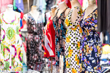 Closeup of many colorful vibrant Italian summer dresses with patterns, colors, hanging on display...
