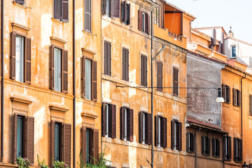 Fototapeta na wymiar Rome, Italy street in historic center facade exterior windows wall during sunny summer day, nobody, orange yellow red old colorful painted walls
