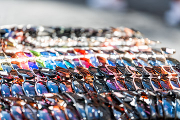 Obraz premium Closeup of many modern sunglasses in outdoor market shop store in Rome, Italy, Europe, outside during summer, shiny reflection