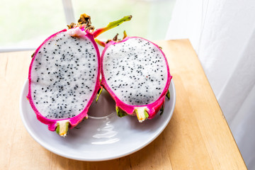 Closeup of cut open pink purple dragon dragonfruit fruit slices halves half inside white flesh,...