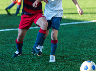 football teams - boys in red, blue, white uniform play soccer on the green field. boys dribbling. dribbling skills. Team game, training, active lifestyle, hobby, sport for kids concept
