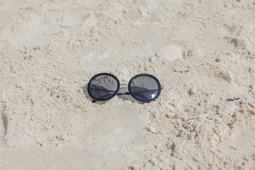 Fototapeta na wymiar Reflecting sunglasses on the beach, glasses in the sand