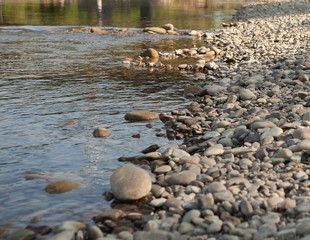 Multicolored stones and gray sand on the river bank. Abstract background