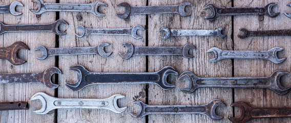 Metal wrench rusty tools lying on a black wooden table. Hammer, chisel, hacksaw, metal wrench. Dirty set of hand tools on a wooden panel vintage background with a tools