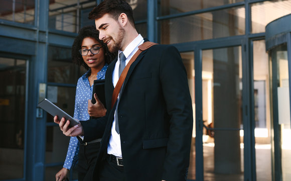 Business Colleagues With Digital Tablet Walking Out Of Office