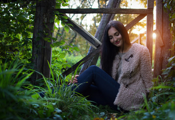 Young beautiful woman girl sitting on the grass near the fence.