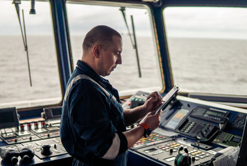 Marine navigational officer or chief mate on navigation watch on ship or vessel. He fills up checklist. Ship routine paperwork