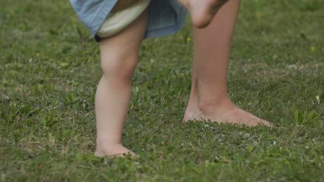Close-up baby barefoot walks on summer green grass. Baby have fun.  Happy family concept.