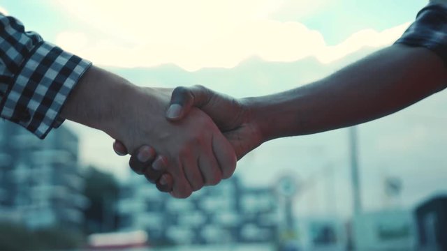 Close up view of multiracial hand shake on unfinished construction background. Cooperation, team work, agreement.