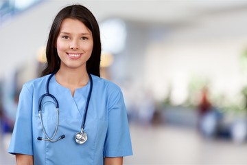Attractive young female doctor with blurred hospital