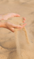 Sand flowing through the woman's hands on the beach