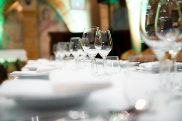 Beautifully decorated table with empty white plates, glasses and cutlery  on luxurious tablecloths
