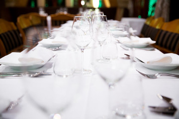 Beautifully decorated table with empty white plates, glasses and cutlery  on luxurious tablecloths