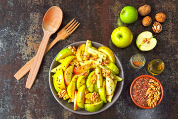 Appetizing apple salad. Vegan bowl of apple salad with walnuts. Healthy autumn salad with apples, nuts, flax seeds and spices.