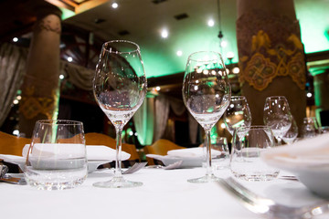 Beautifully decorated table with empty white plates, glasses and cutlery  on luxurious tablecloths