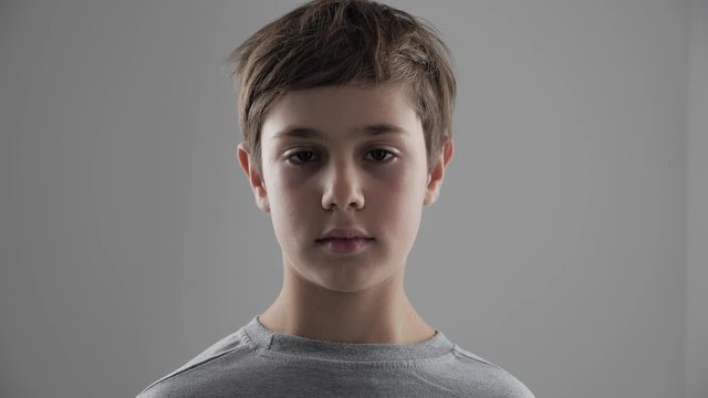Portrait of cute young 11 - 12 year old boy looking at the camera on white background