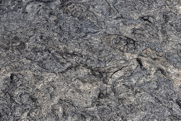 Aerial view of Puu Ooo Volcanic pahoehoe lava field from recent eruption. The surface is swirled and wrinkled; it's smooth metalic surface reflecting silver. Giant cracks from cooling. 
