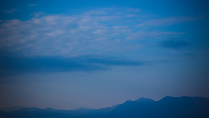 Fototapeta na wymiar vivid mountain silhouette horizon line scenery nature landscape in evening twilight time and soft blue fog everywhere, copy space wallpaper