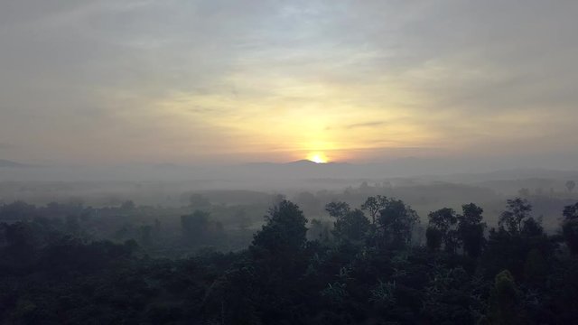 Flying across the horizon through the fog and clouds looking at the most beautiful morning sunrise in Chiang Rai Thailand